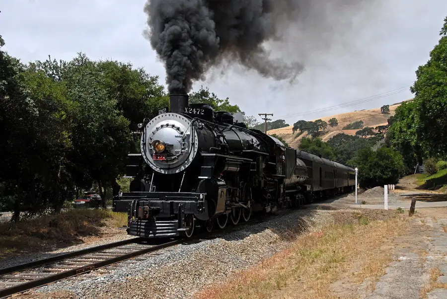A passenger train curving through a green valley