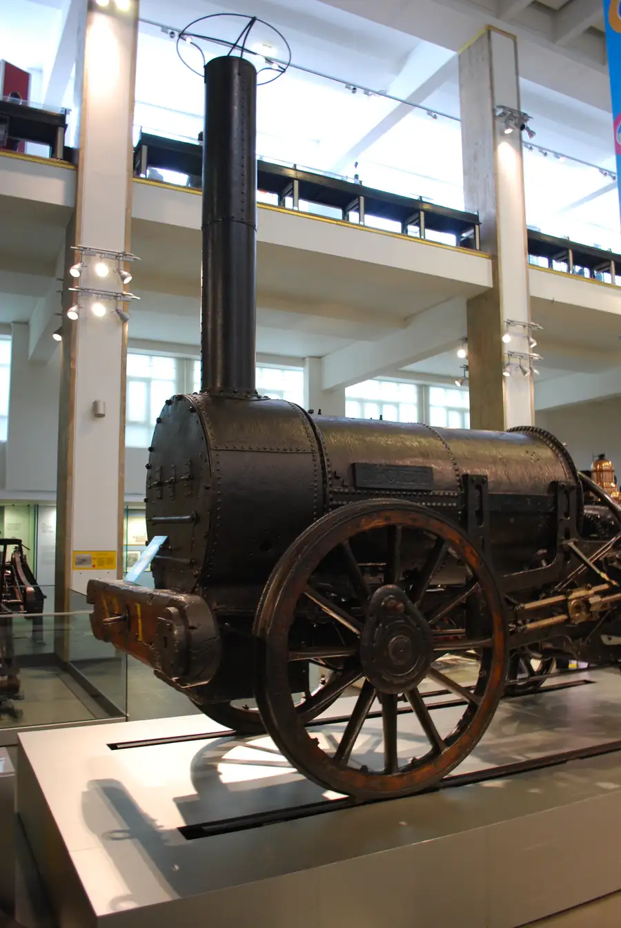 Stephenson's Rocket, a small yellow early steam locomotive with a tall smokestack