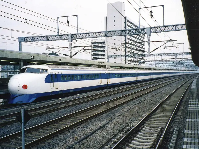 A white and blue 0 Series Shinkansen with its rounded bullet-shaped nose