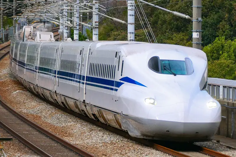 A modern white N700S Shinkansen with blue stripes and a long pointed nose
